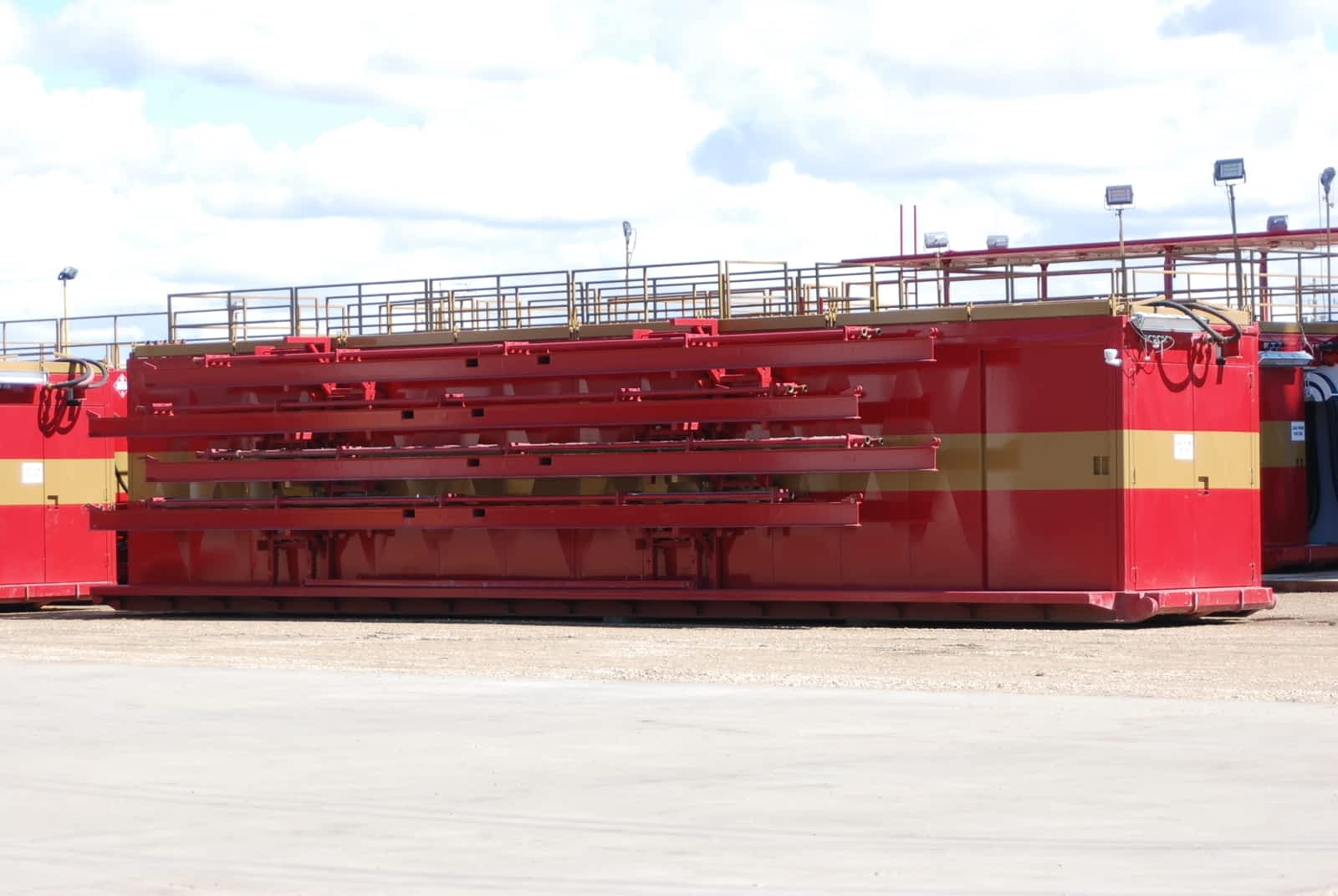 A glossy red drilling rig building with a gold strip sitting
                in an industrial yard.