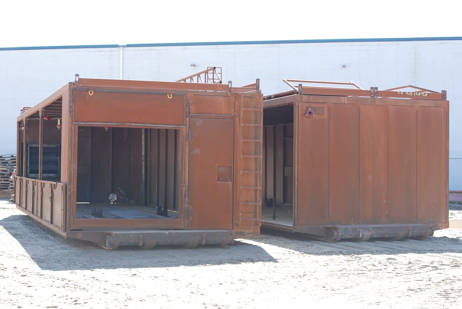 Two unpainted, rusty new construction drilling rig generator
                    buildings.